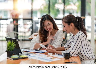 Two pretty young Asian businesswoman sitting at desk with laptop doing paperwork together discussing project financial report. Corporate business collaboration concept. - Shutterstock ID 2123916485