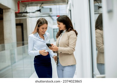 Two pretty young business women with mobile phone in the office hallway - Powered by Shutterstock