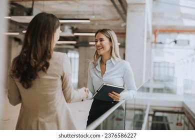 Two pretty young business women with paper notebook in the office hallway - Powered by Shutterstock