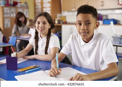 Two Primary School Pupils In Classroom Looking To Camera