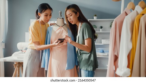 Two professional Asia cheerful lady fashion designer teamwork with casual hold dummy look smartphone share idea create beautiful dress in shop. Lady tailor business partner start up business store. - Powered by Shutterstock