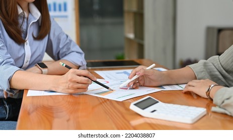 Two Professional Asian Female Financial Consultants Discussing And Working Together On A Business Financial Report. Cropped Shot