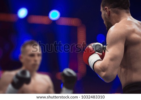 Two professional boxers, athletes in dynamic boxing action on the ring under lights of sport arena.