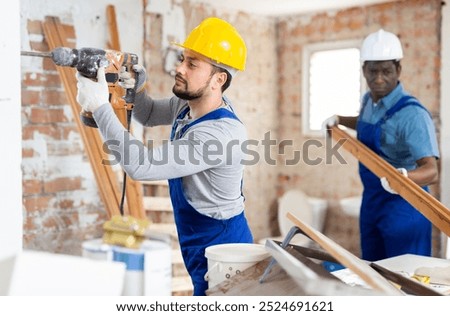 Two professional builders work on the construction site indoors, performing major repairs in the house