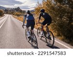 Two professional cyclist racers. Close up back view of cycling group training on a road bicycles at sunset in the mountains.Training for competition.Practicing cycling on open country road.Spain