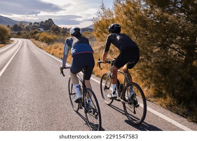 Two professional cyclist racers. Close up back view of cycling group training on a road bicycles at sunset in the mountains.Training for competition.Practicing cycling on open country road.Spain - Powered by Shutterstock