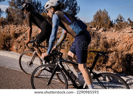 Two professional cyclist racers. Close up back view of cycling group training on a road bicycles at sunset in the mountains.Training for competition.Practicing cycling on open country road.Spain
