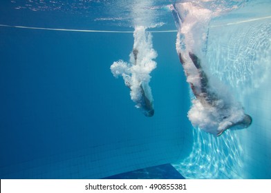 Two Professional Divers Enter The Water After A Synchronized Back Flip Dive. Underwater Shot, Convenient Copy Space On The Left.