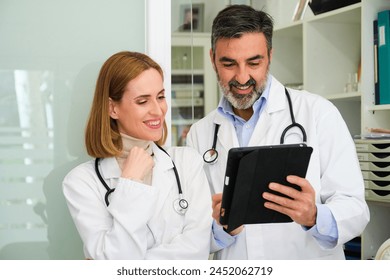 Two professional doctors talking about medical reports and using a tablet at office. - Powered by Shutterstock