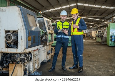 Two professional engineer worker technician checking old machine construction factory with colleague technician. factory assistant worker in helmet check old machinery construction in old factory.