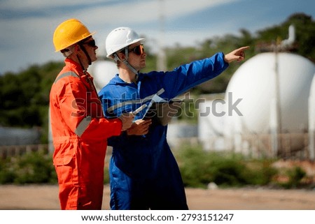 two professional engineer, worker, technician use clipboard discuss work, discussing operations at a gas storage facility. protective uniforms and helmets. industry, engineer, safety, teamwork, energy