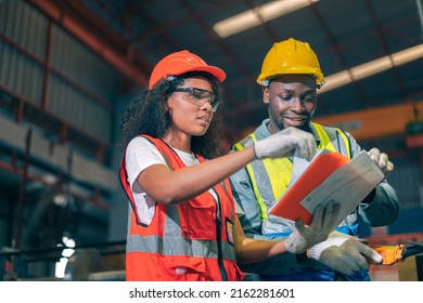 Two Professional Engineer,worker,technician Use Clipboard Discuss Work, Walk In Steel Metal Manufacture Factory Plant Industry. Black African American Man And Woman Wear Hard Hat Check Quality Machine