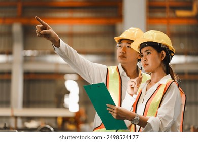 two professional engineer,worker,technician use clipboard discuss work, walk in steel metal manufacture factory plant industry. Black African American man and woman wear hard hat check quality machine - Powered by Shutterstock