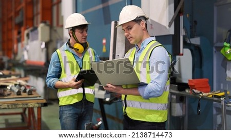 Two professional industrial engineer specialist with safety vast uniform and helmet holding laptop checking security of electrical control panel in private sector of industry safety security concept  