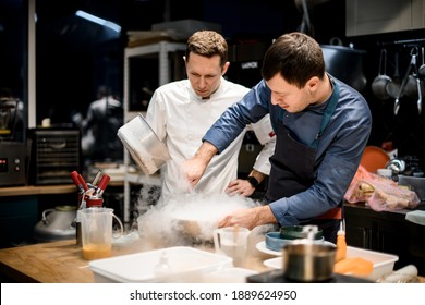 two professional male chefs preparing molecular cuisine dish in the kitchen. A lot of smoke and steam around them - Powered by Shutterstock