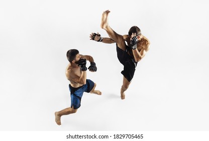 Two professional MMA fighters boxing isolated on white studio background. Top view of couple of muscular athletes. Sport, healthy lifestyle, competition, dynamic and motion, action concept. Copyspace.