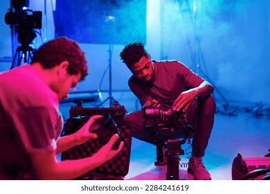 Two professional photographers setting cameras before shooting while working in studio - Powered by Shutterstock