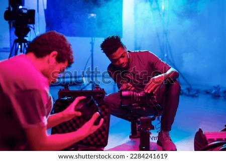 Two professional photographers setting cameras before shooting while working in studio