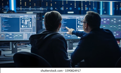 Two Professional IT Programers Discussing Blockchain Data Network Architecture Design and Development Shown on Desktop Computer Display. Working Data Center Technical Department with Server Racks - Shutterstock ID 1590824917
