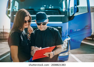 Two Professional Truck Drivers Stand In Front Of The Big Truck. They Talk And Perform A Technical Inspection Of The Vehicle Before Next Drive. Professional Transportation Concept.