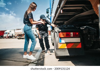 Two Professional Truck Drivers Stand In Front Of The Big Truck. They Talk And Perform A Technical Inspection Of The Vehicle Before Next Drive. Professional Transportation Concept.