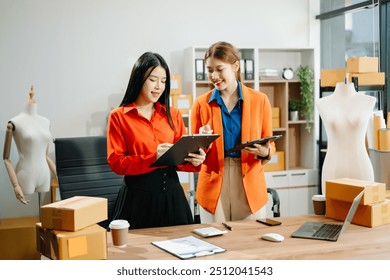 Two professional young Asia cheerful lady fashion designer teamwork with casual site on table use tablet meeting discuss final design share idea in shop. and holds tablet and laptop. 
 - Powered by Shutterstock