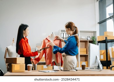 Two professional young Asia cheerful lady fashion designer teamwork with casual site on table use tablet meeting discuss final design share idea in shop. and holds tablet and laptop. 
 - Powered by Shutterstock