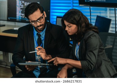 Two professionals analyze and discuss programming code displayed on screen in modern tech workspace. Capturing a collaborative environment focused on software development, debugging, and teamwork