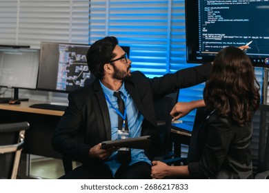 Two professionals analyze and discuss programming code displayed on screen in modern tech workspace. Capturing a collaborative environment focused on software development, debugging, and teamwork