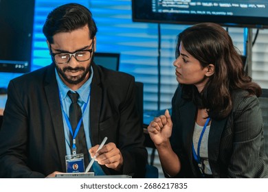 Two professionals analyze and discuss programming code displayed on screen in modern tech workspace. Capturing a collaborative environment focused on software development, debugging, and teamwork