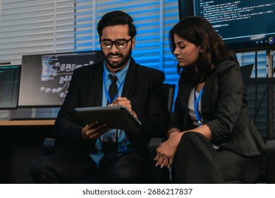 Two professionals analyze and discuss programming code displayed on screen in modern tech workspace. Capturing a collaborative environment focused on software development, debugging, and teamwork