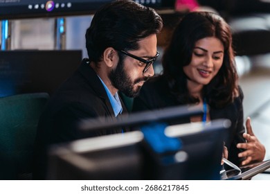 Two professionals analyze and discuss programming code displayed on screen in modern tech workspace. Capturing a collaborative environment focused on software development, debugging, and teamwork