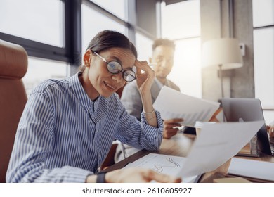 Two professionals analyze documents in a modern workspace, emphasizing the importance of collaboration and teamwork