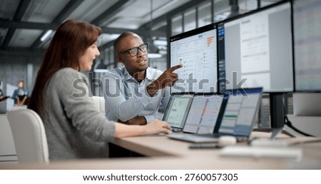 Two Professionals Analyzing Financial Reports And Tracking Data On Computer Screens