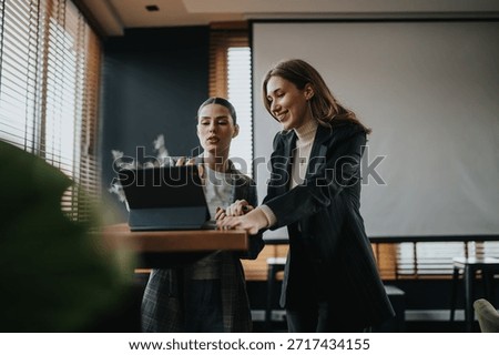 Two professionals collaborate over a tablet in a contemporary office, sharing ideas and discussing tasks. The scene captures teamwork, mentorship, and a positive, productive work atmosphere.
