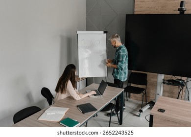 Two professionals discuss data analysis during a business meeting with a flipchart.