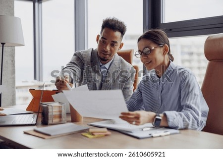Two professionals discuss essential documents in a modern office to enhance collaboration and productivity