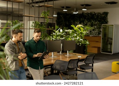 Two professionals are engaged in a focused conversation while holding digital tablet in a contemporary office space, featuring rustic exposed brickwork and warm natural light - Powered by Shutterstock