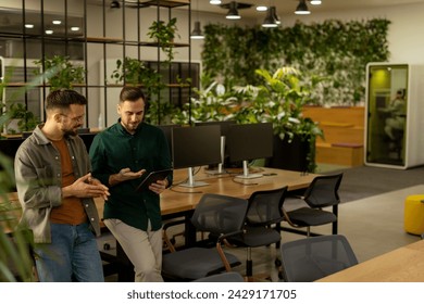 Two professionals are engaged in a focused conversation while holding digital tablet in a contemporary office space, featuring rustic exposed brickwork and warm natural light - Powered by Shutterstock