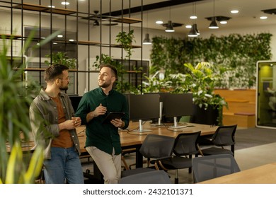 Two professionals are engaged in a focused conversation while holding digital tablet in a contemporary office space, featuring rustic exposed brickwork and warm natural light - Powered by Shutterstock