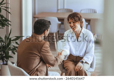 Two professionals engaged in a handshake during a formal meeting, highlighting collaboration and agreement.