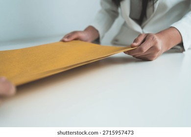 Two professionals exchanging a document envelope during a formal business or legal transaction, symbolizing agreement, trust, and confidential paperwork. - Powered by Shutterstock - Get 15% off with code: PIKWIZARD15