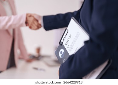 Two professionals finalize a job interview with a firm handshake. This signifies new employment and successful hiring process.