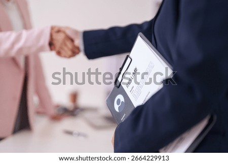 Two professionals finalize a job interview with a firm handshake. This signifies new employment and successful hiring process.