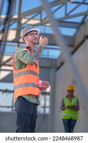 Two professionals inspect construction site of commercial building, industrial building, real estate project  civil engineer, investor using laplet in background crane, skyscraper, concrete formwork - Shutterstock ID 2248468987
