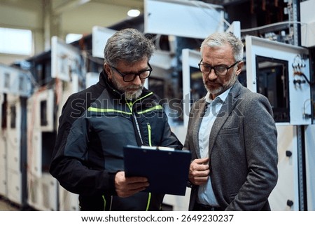 Two professionals reviewing technical data in a modern industrial equipment environment