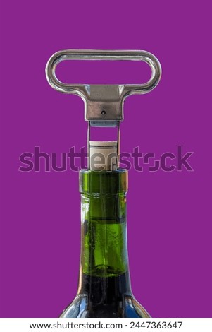 Two prong cork puller and cork halfway pulled from green wine bottle