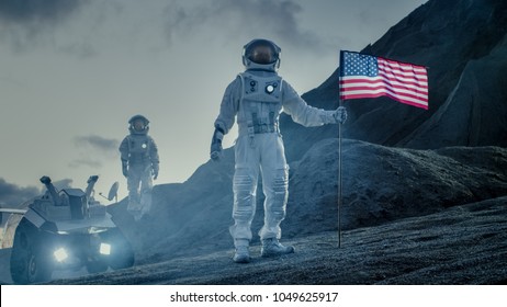 Two Proud Astronauts Plant American Flag On The Alien Planet. In The Background Research Base And Rover.