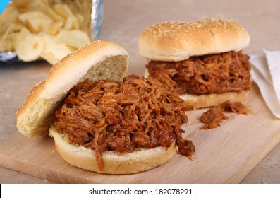 Two pulled pork barbecue sandwiches on a cutting board