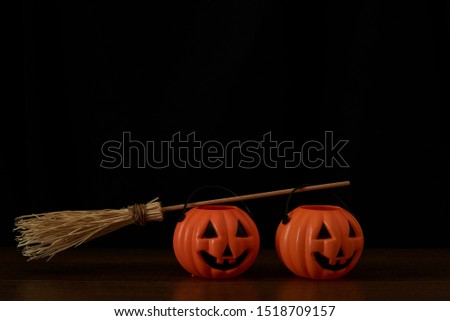 Two pumpkins and a witch broom on black background. Happu halloween